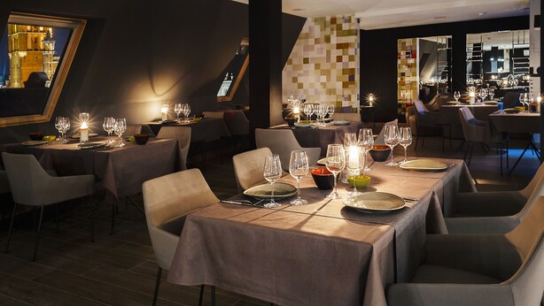 A restaurant with tables set for dining, featuring a modern interior with geometric wall patterns and a view of a historic building through a large window. - B&B HOTEL Gdańsk Old Town (Gdansk)