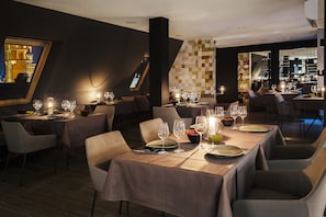 A restaurant with tables set for dining, featuring a modern interior with geometric wall patterns and a view of a historic building through a large window. - B&B HOTEL Gdańsk Old Town (Gdansk)