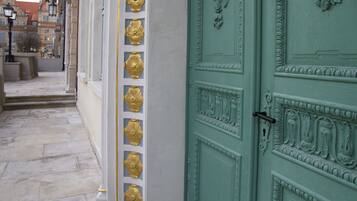 A green door with gold decorative elements and a white wall with similar gold accents.