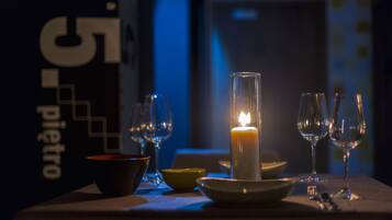 A candlelit table with glasses and bowls, a sign with '55' and 'pietro' visible, and a dimly lit background.