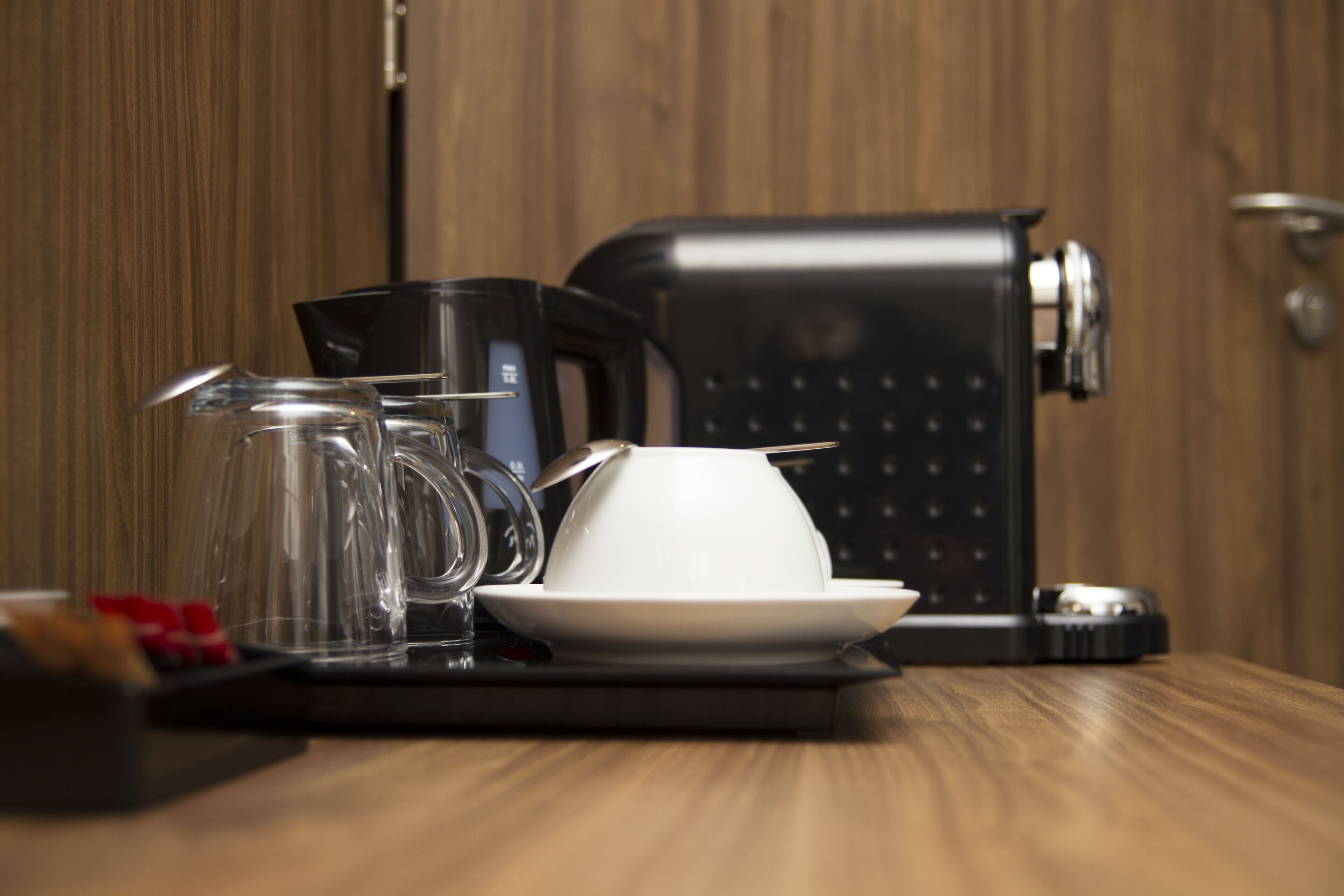 Una cafetera, un jarro de vidrio y una taza blanca sobre una bandeja.