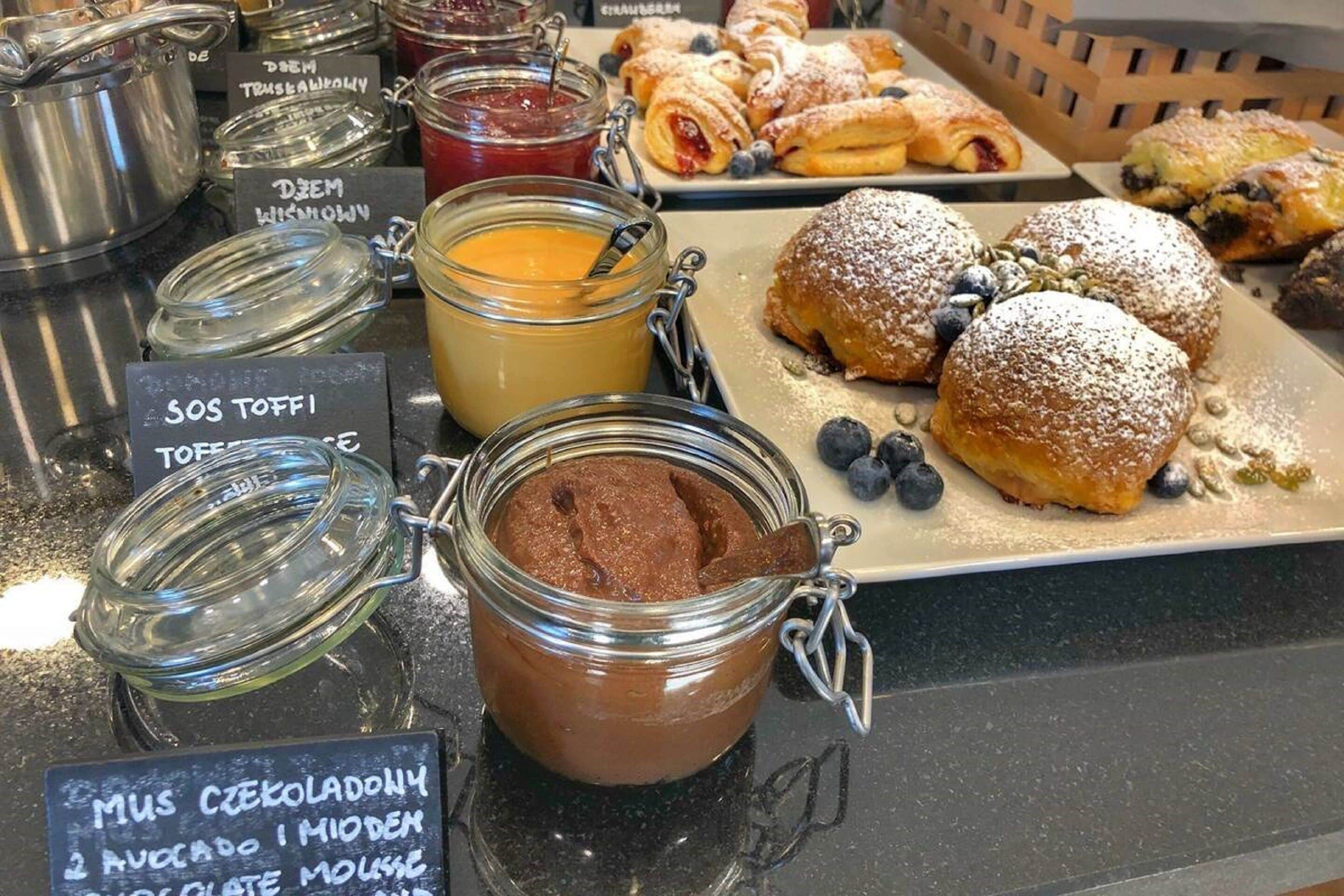 Una exhibición de diversos alimentos, como pasteles, mermeladas y un mousse de chocolate.