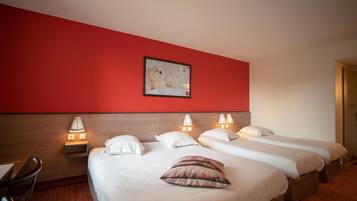 Habitación de hotel con dos camas, una pared de acento roja y un cuadro enmarcado sobre las camas.