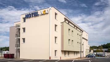 Un edificio moderno de hotel con fachada plana, múltiples ventanas y un letrero que dice "HOTEL LACE".