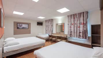 A hotel room with two single beds, a desk with a chair, a mirror, and a television.