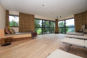 A modern room with large windows, a wooden floor, a bench, and a table.