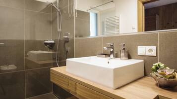 A modern bathroom with a large rectangular sink, a glass shower enclosure, and a wooden vanity.