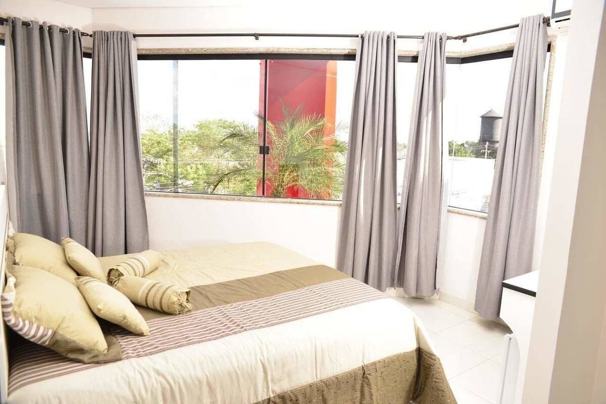 A bedroom with a bed, pillows, and curtains.