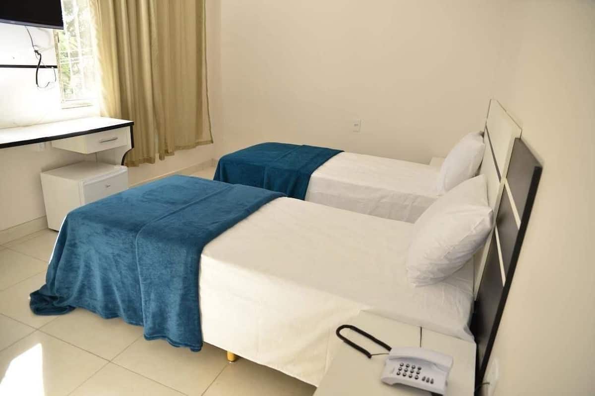 A hotel room with two beds, a desk, and a telephone.