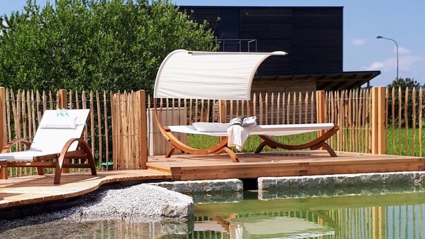 A pool area with lounge chairs and a wooden deck. - Hotel der Freiraum (Guessing)