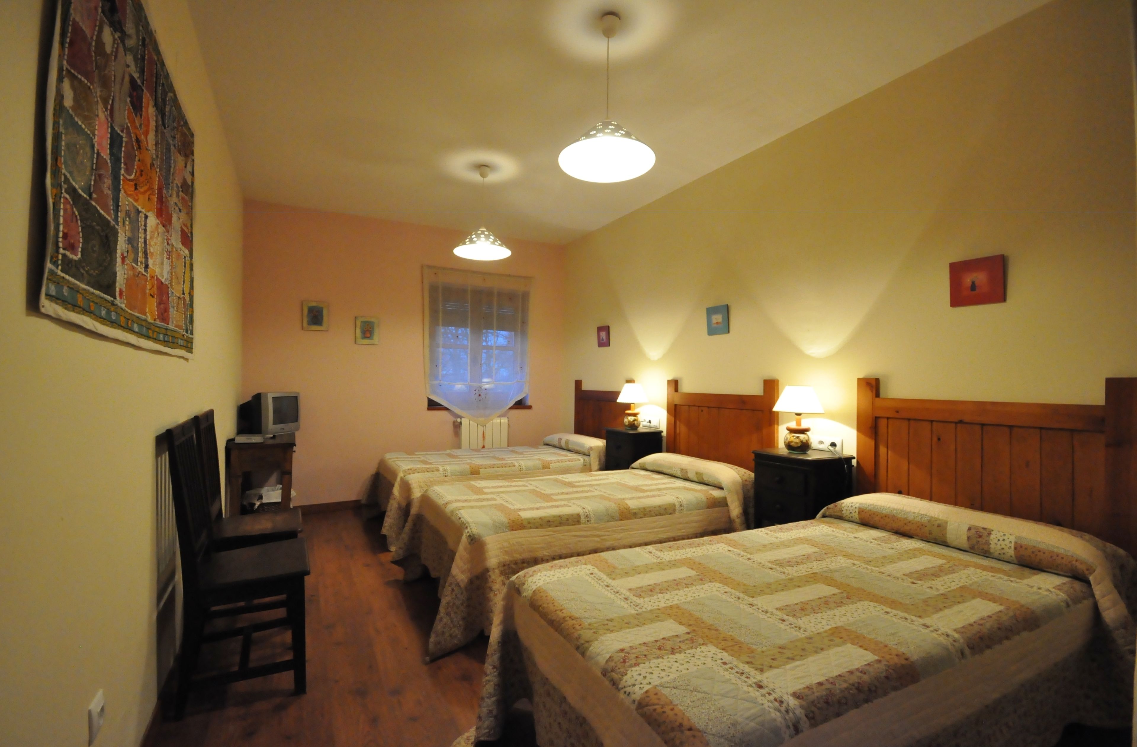 Habitación de hotel con dos camas, un escritorio con computadora y una ventana con persianas.