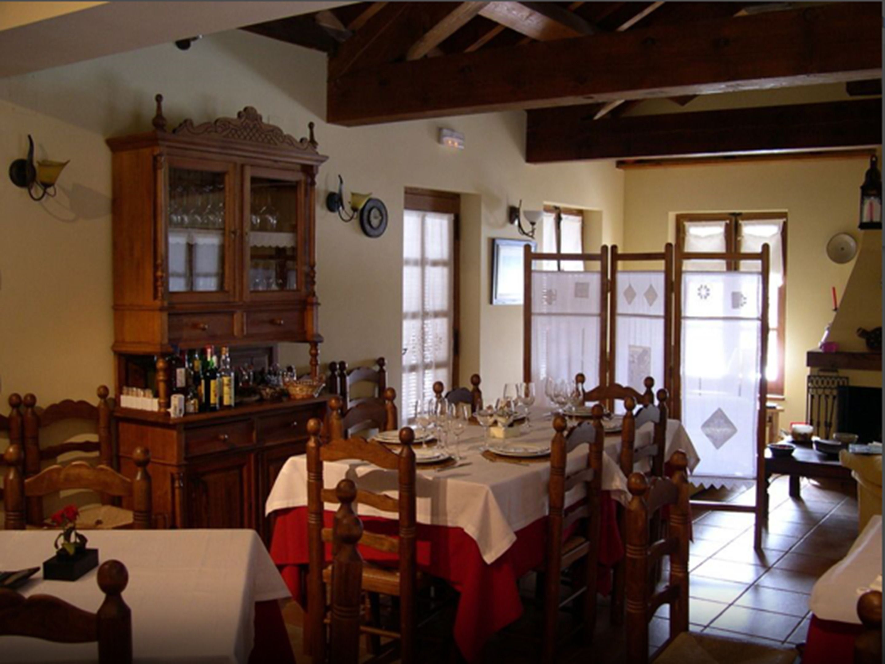 Un comedor con mobiliario de madera, un armario con puertas de vidrio y una mesa dispuesta para una comida.