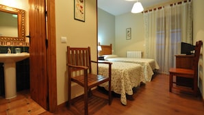 A room with two beds, a wooden chair, a desk, a mirror, and a sink. - Hotel Rural Aguallevada (Robleda-Cervantes)