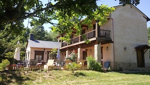 A two-story building with a balcony, stone pillars, and a wooden fence. - Hotel Rural Aguallevada (Robleda-Cervantes)