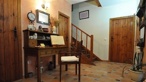 A wooden desk with a chair, a clock, and a mirror. There is a staircase with wooden railings leading to another room. - Hotel Rural Aguallevada (Robleda-Cervantes)