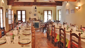 A dining area with wooden beams, tables set for a meal, and chairs. - Hotel Rural Aguallevada (Robleda-Cervantes)
