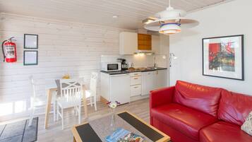 Un espacio habitable compacto con kitchenette, zona de comedor y sofá de cuero rojo.
