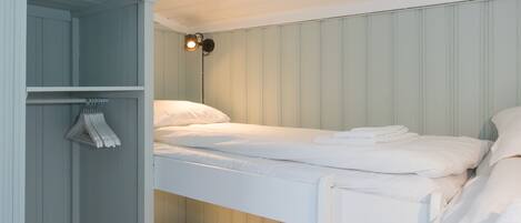 A bunk bed room with a wardrobe and a hanging rack.