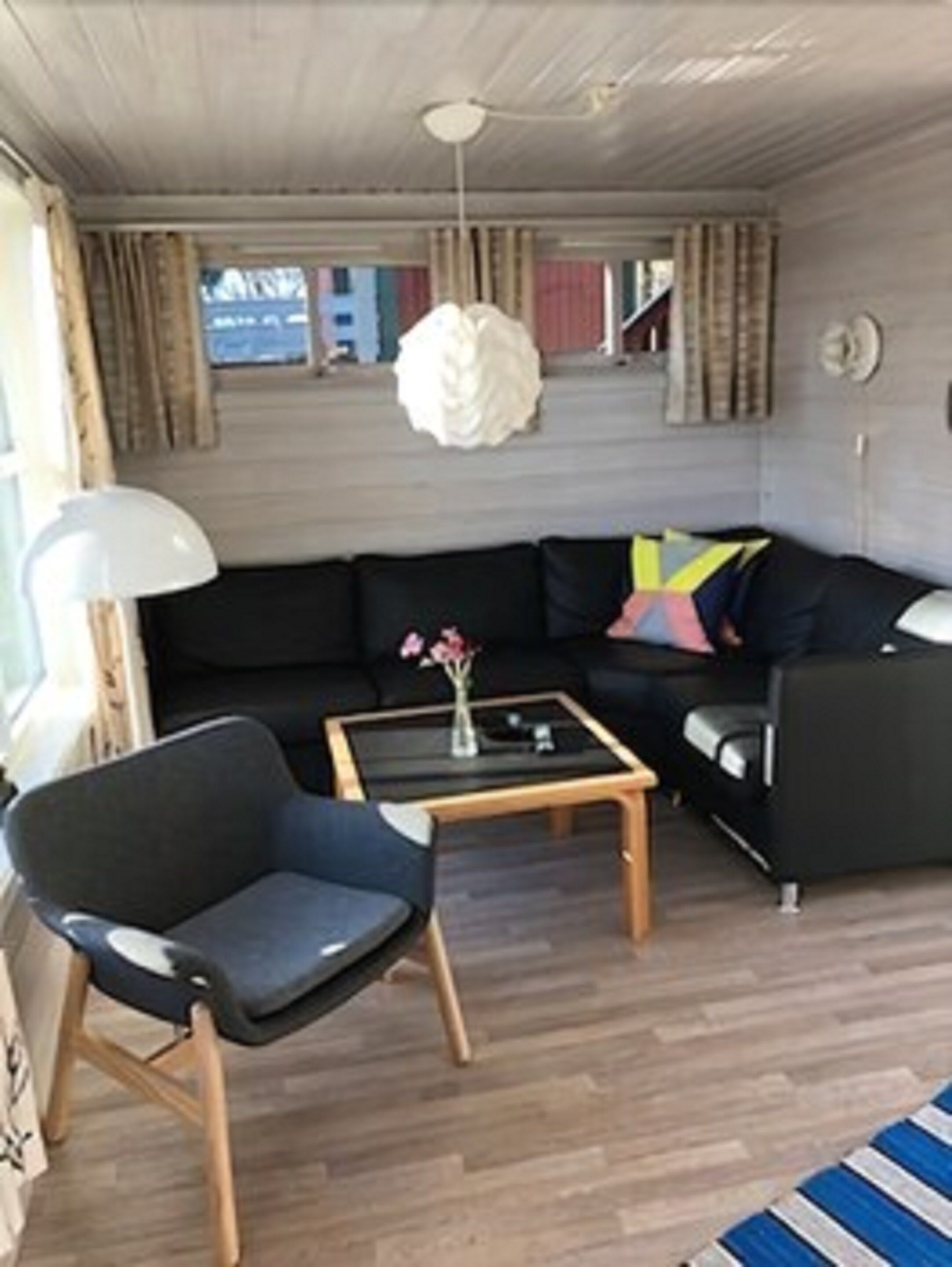 Un salon moderne avec un canapé noir, une table basse en bois et un fauteuil noir.