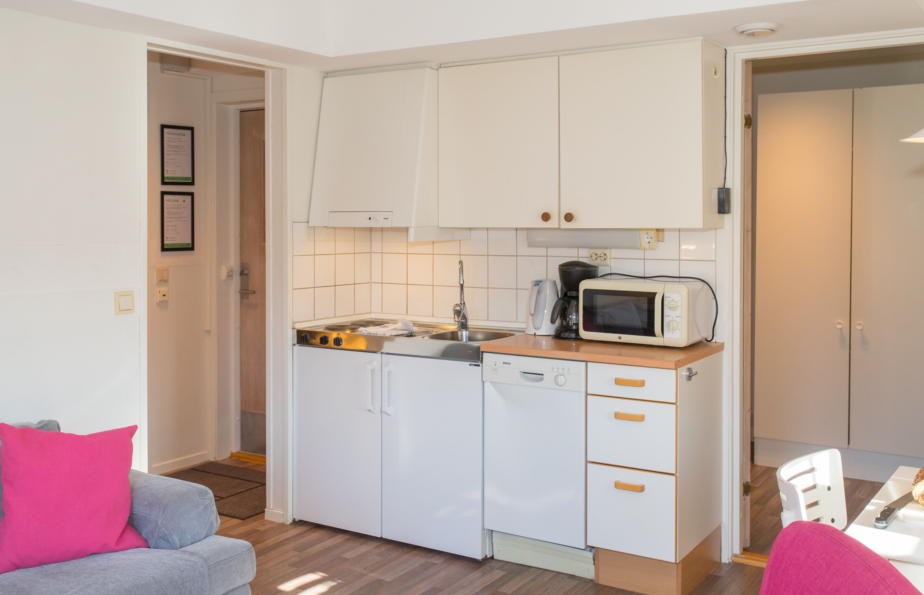 A compact kitchen with white cabinets, a microwave, and a coffee maker.
