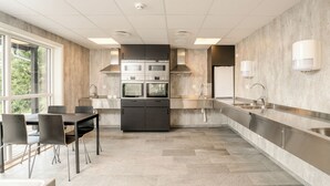 Una cocina moderna con comedor, hornos empotrados y un amplio ventanal.