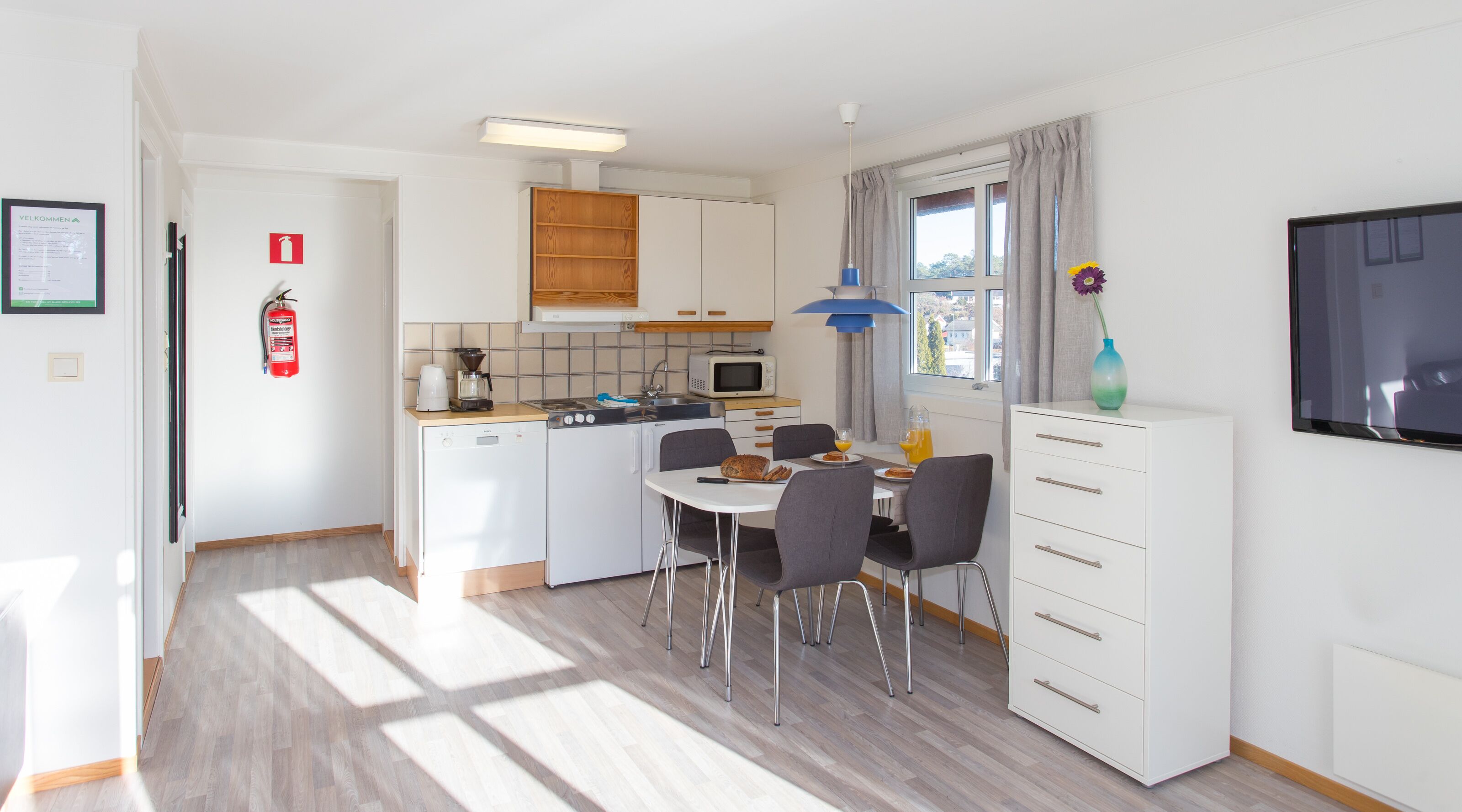 A compact kitchen with a dining area, a microwave, a coffee maker, and a small refrigerator.