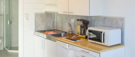 A compact kitchen with white cabinets, a microwave, a sink, and a wooden countertop.