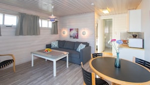 Un espacio habitable compacto con sofá, una mesa de centro de vidrio, una mesa de comedor y un rincón americano.