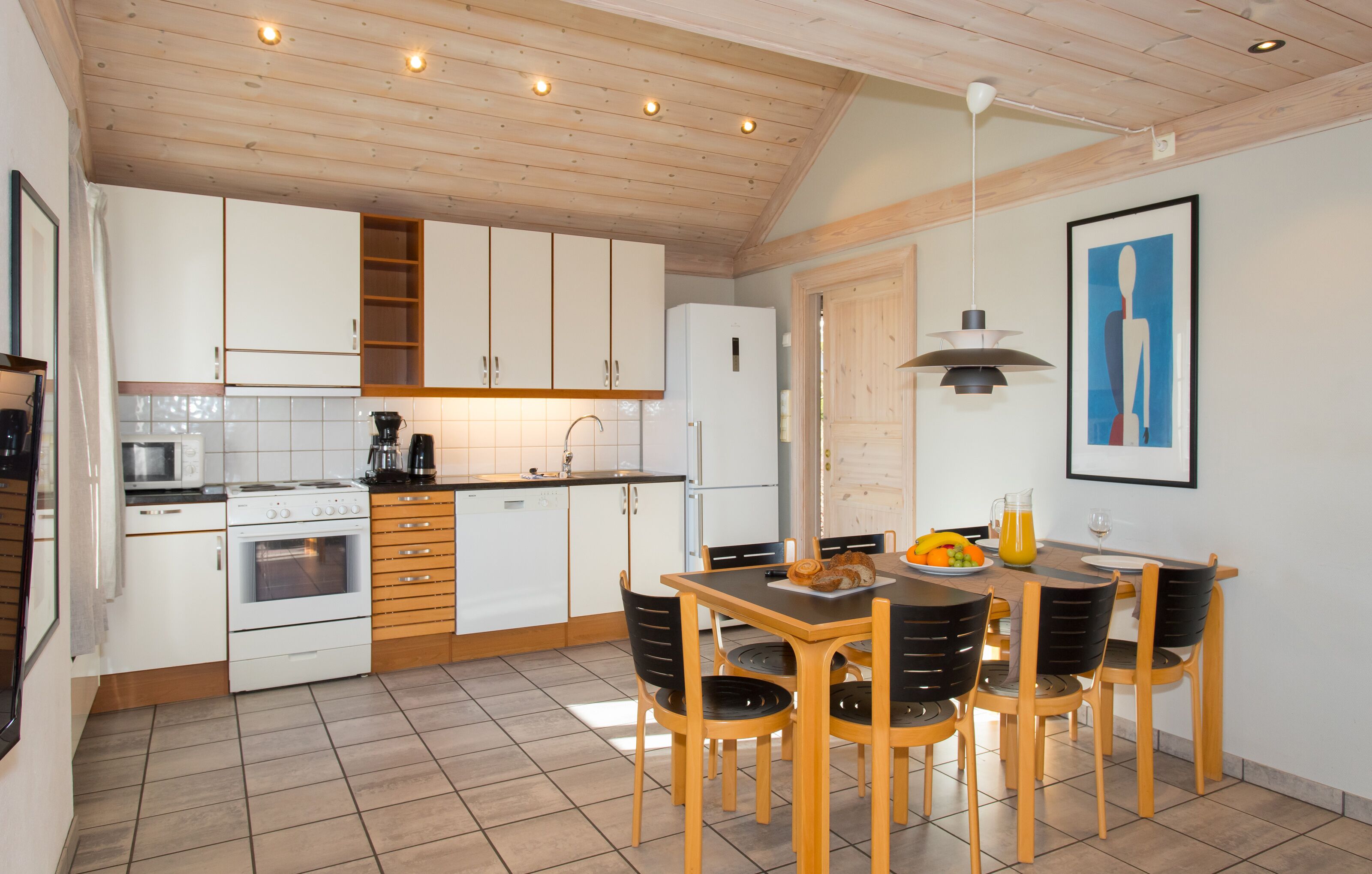 A kitchen with white cabinets, a stove, a refrigerator, and a dining table with chairs.