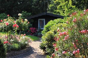 A garden pathway leading to a small building with a dark roof and a door.