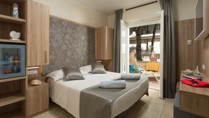 Quarto de hotel com uma cama, uma mesa de trabalho, uma televisão e vista para a varanda.