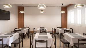 A conference room with multiple tables and chairs, ceiling lights, and a flat-screen TV mounted on the wall. - Hotel Barba (Starigrad)