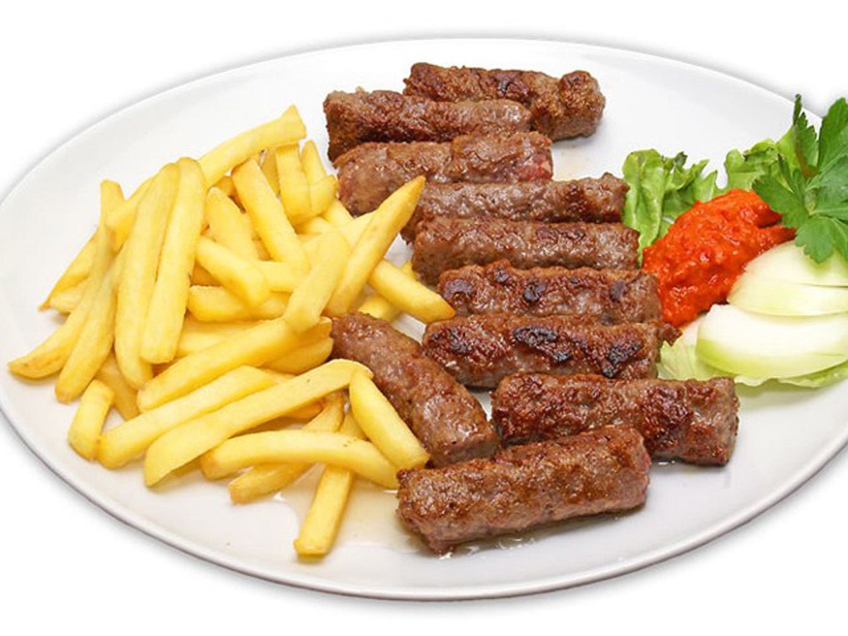 Un plato con carne a la parrilla, papas fritas y una ensalada.