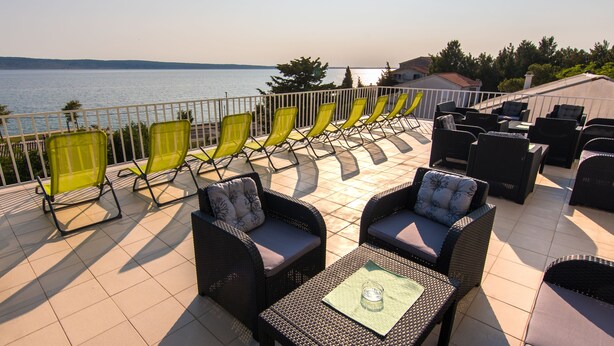 A terrace with outdoor seating, a view of the sea, and a tiled floor. - Hotel Barba (Starigrad)