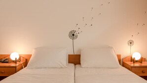 A double bed with white linens, two bedside tables with lamps, and wall art of dandelions. - Hotel Barba (Starigrad)
