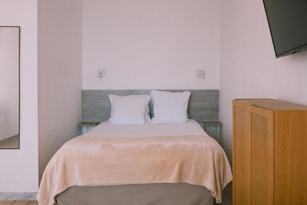 A bedroom with a bed, a wooden nightstand, a television mounted on the wall, and a wardrobe. - Creste e Mare (Ajaccio)