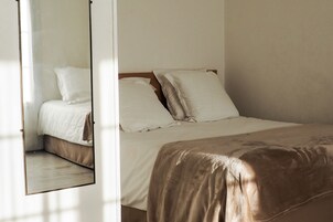 Un dormitorio con cama, almohadas y un espejo.