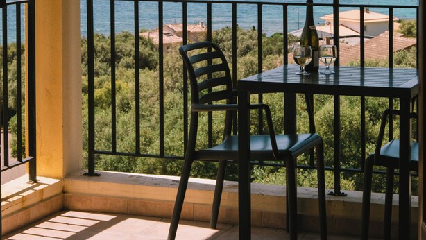 A balcony with a view of the sea, a table with chairs, and a bottle of wine. - Creste e Mare (Ajaccio)