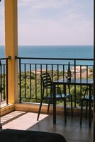 Un balcón con vistas al mar, una mesa con sillas y una botella de vino.