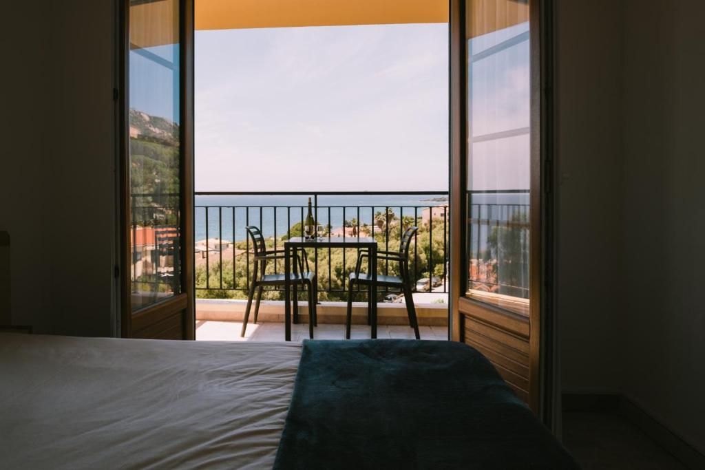 Et værelse med en seng, et bord med stole og en balkon med havudsigt.