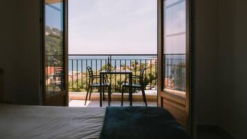 Una habitación con cama, una mesa con sillas y un balcón con vista al mar.