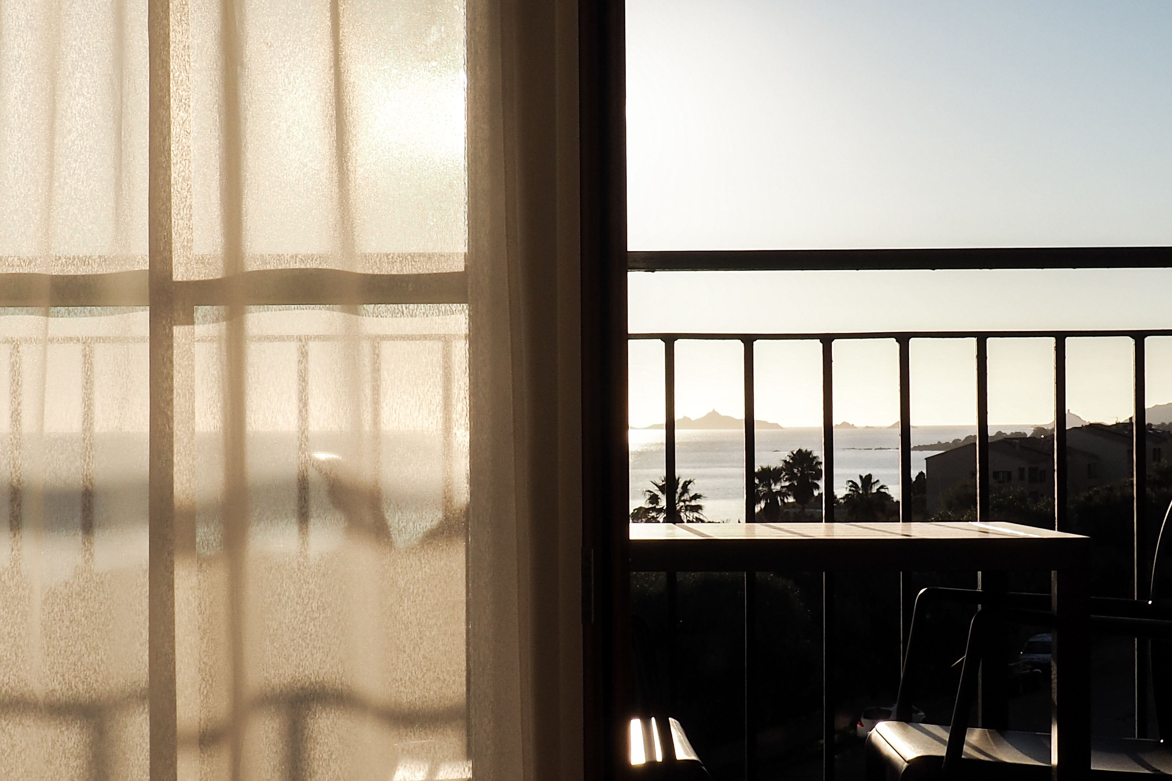 A balcony with a view of the ocean and mountains.