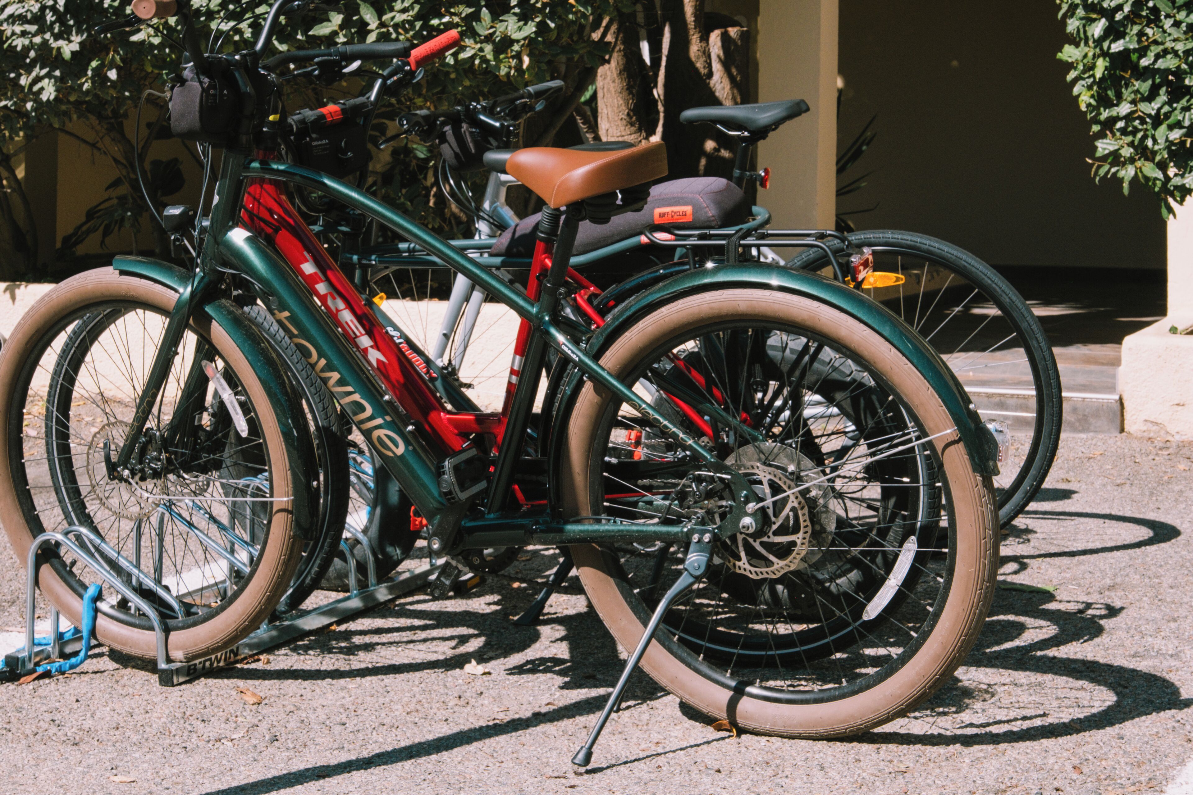 A bicycle with a red frame and a brown seat parked on a paved surface.