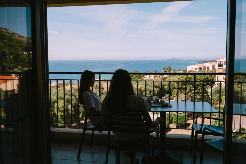 Dos personas sentadas a una mesa con vista al mar y edificios al fondo.
