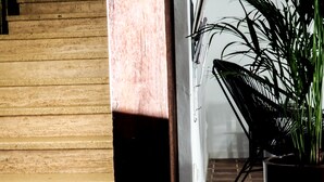 A wooden wall with a door leading to a room with a chair and a potted plant. - Creste e Mare (Ajaccio)