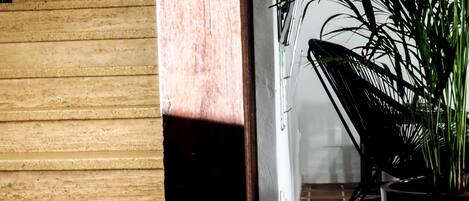 Pared de madera con una puerta que da a una habitación con una silla y una planta en maceta.