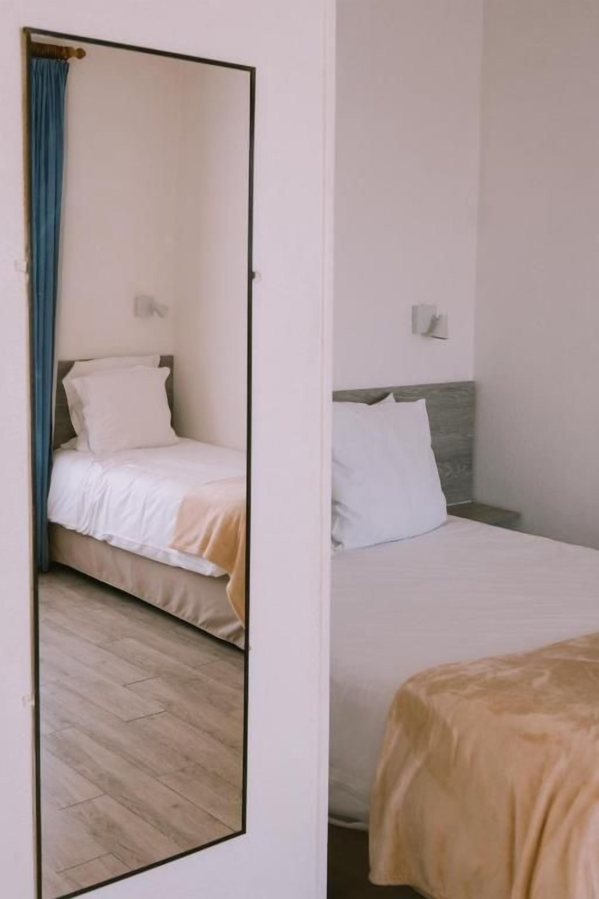 Een kamer met een bed, een spiegel en een houten vloer.