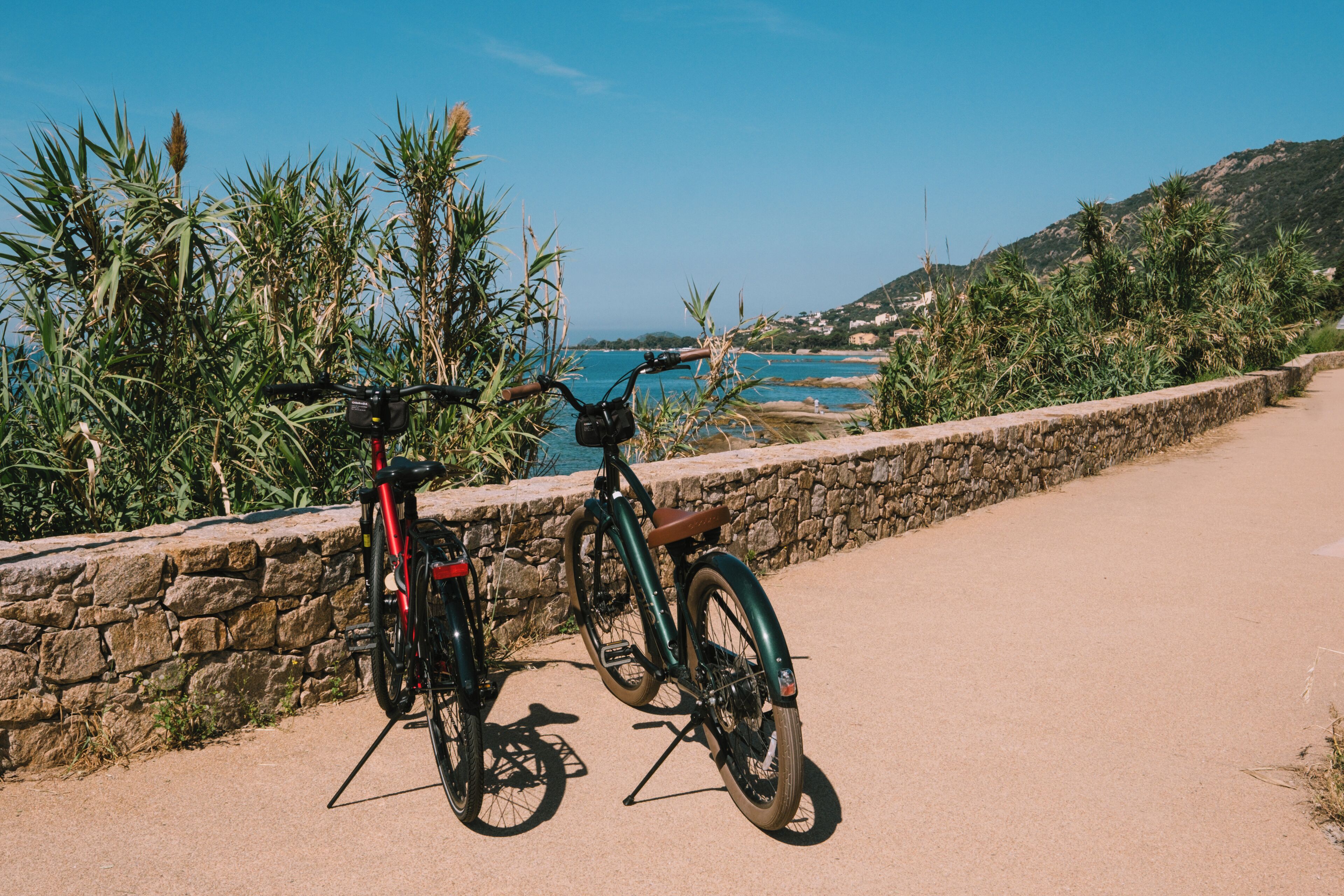 A coastal path with two bicycles parked on a stone wall.