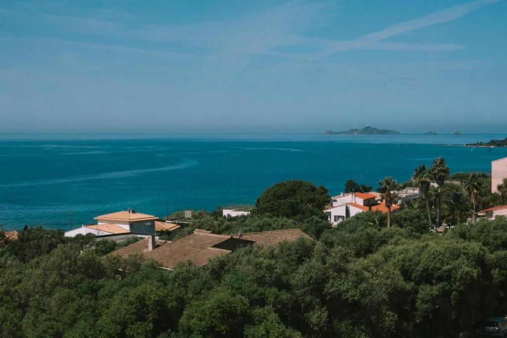 Un quartier résidentiel situé sur la côte, avec des maisons, une végétation luxuriante et une vue sur la mer.
