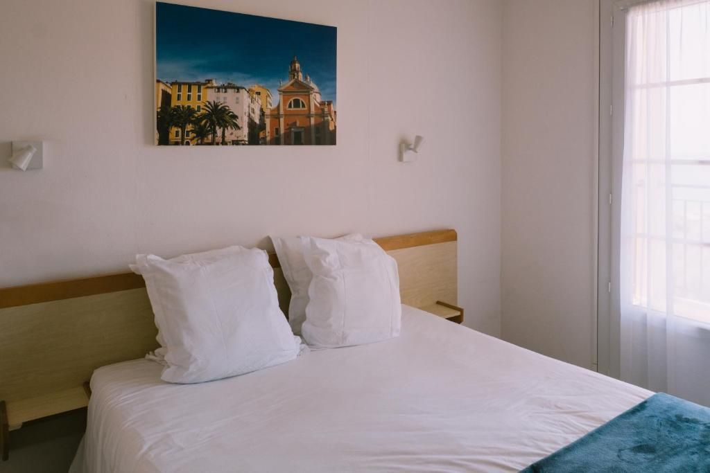 Una habitación de hotel con cama, un cuadro en la pared y una ventana.